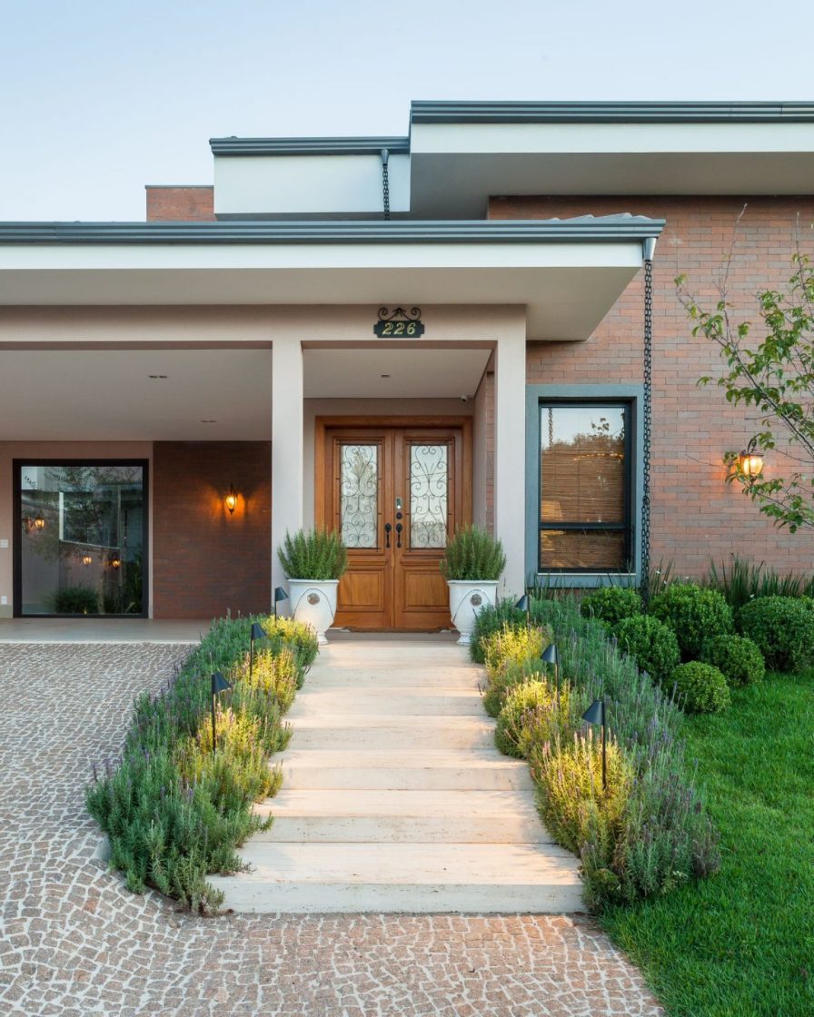 Fachada com porta de madeira e escadaria com vegetação
