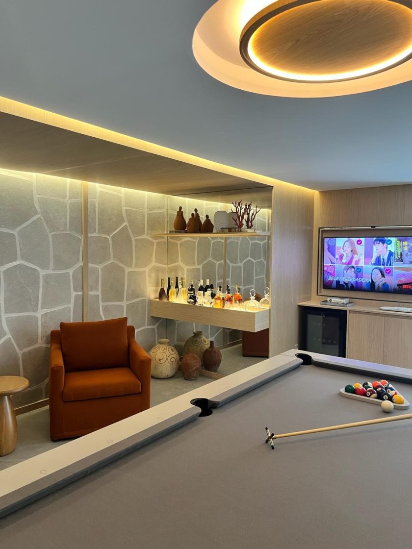 Sala de jogos com mesa de sinuca, poltrona, minibar e televisão