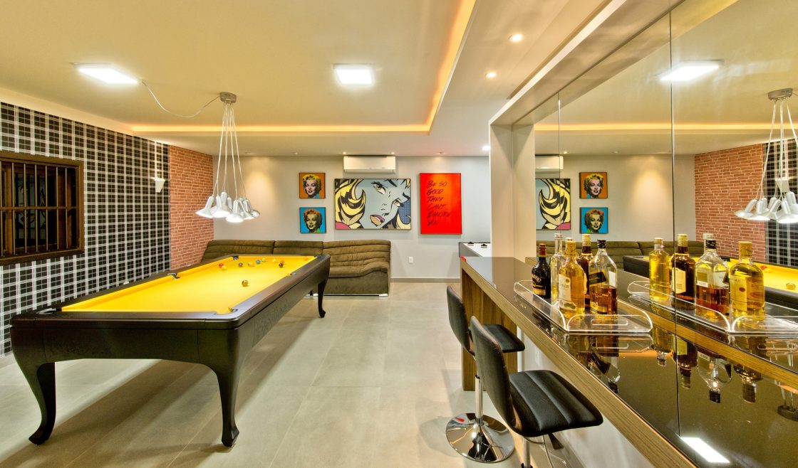 Sala de jogos com minibar e mesa de sinuca amarela