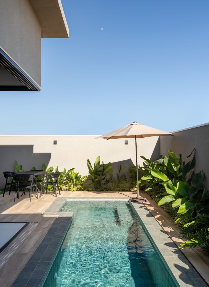 Área externa com piscina de alvenaria e revestimento amadeirado no entorno
