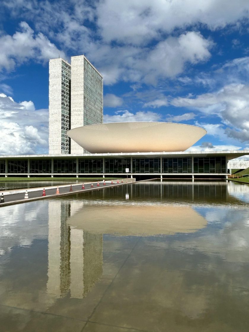 Vista do Congresso Nacional, em Brasília, com suas formas geométricas marcantes refletidas no espelho d'água