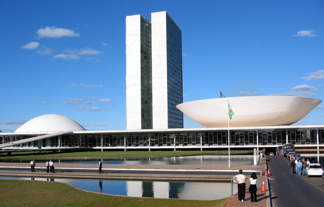 Vista frontal do Congresso Nacional, em Brasília, com as torres gêmeas ao centro, a cúpula convexa do Senado e a cúpula côncava da Câmara dos Deputados