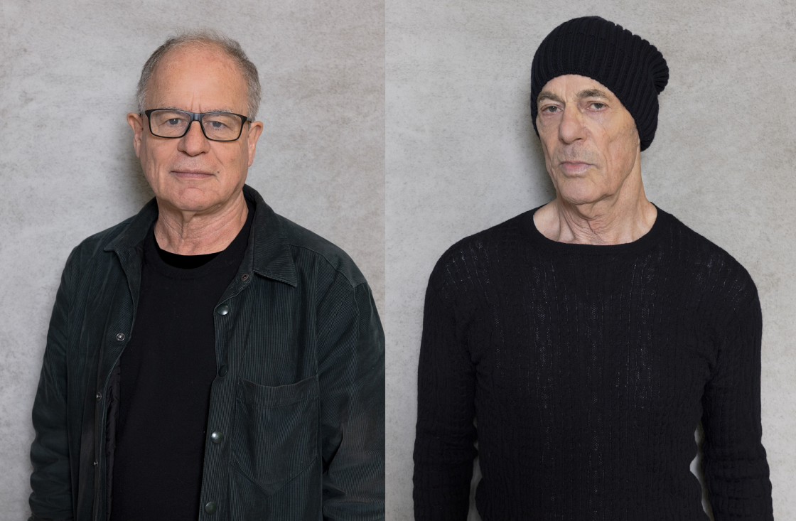 Retrato lado a lado de Jacques Herzog e Pierre de Meuron; à esquerda, Herzog usa óculos e jaqueta escura; à direita, de Meuron veste suéter preto e gorro, ambos posando diante de um fundo neutro