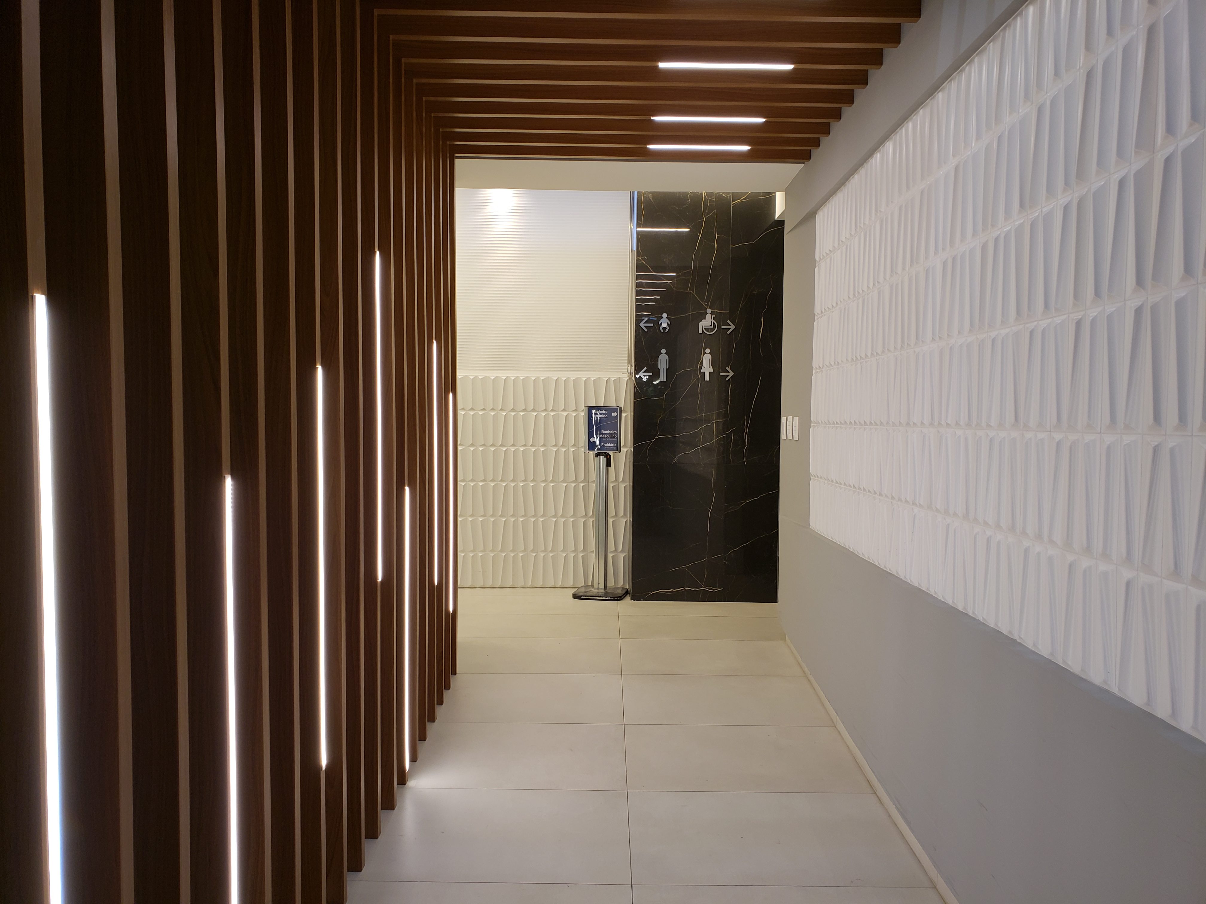 Hall de acesso aos novos banheiros do Aeroporto Internacional de Florianópolis. No piso, porcelanato natural da linha Superquadrada (Portobello) e na parede do hall, porcelanato decorativo Madam MAatt White, da Linha 3D Lab (Portobello). Foto: Floripa Airport/Divulgação