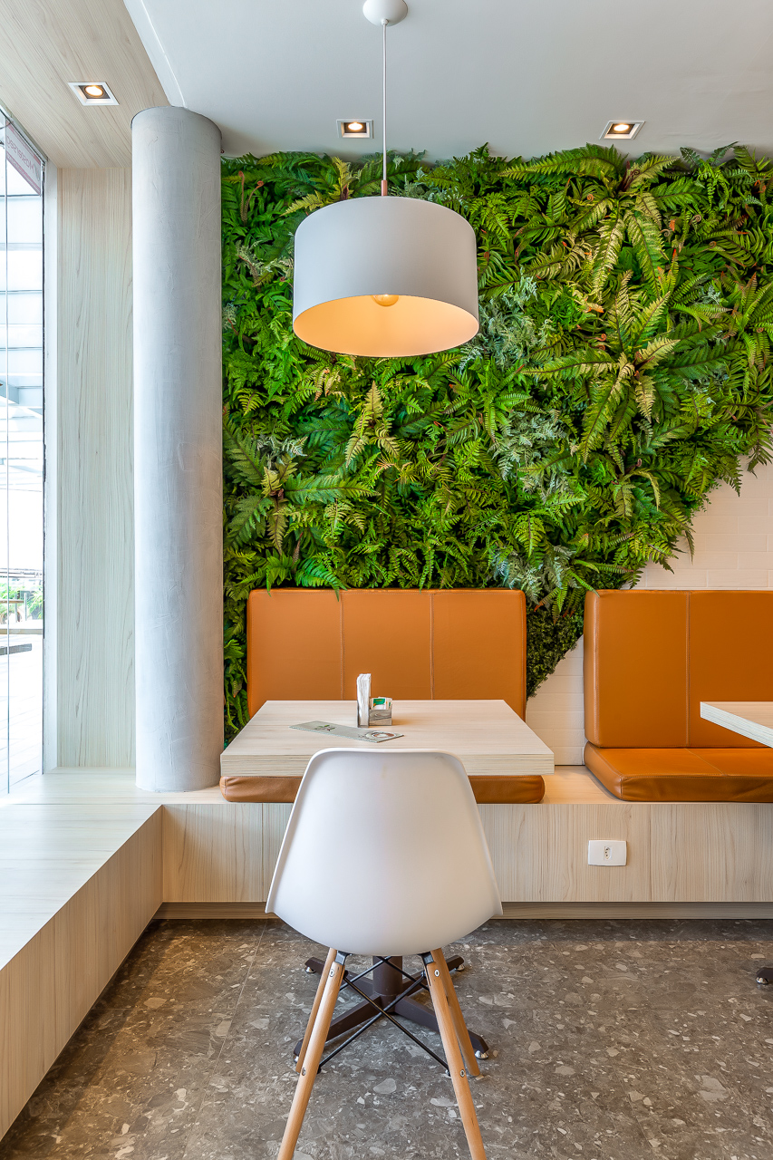 Cafeteria com móveis em madeira e jardim vertical (Foto: Projeto Archibox)
