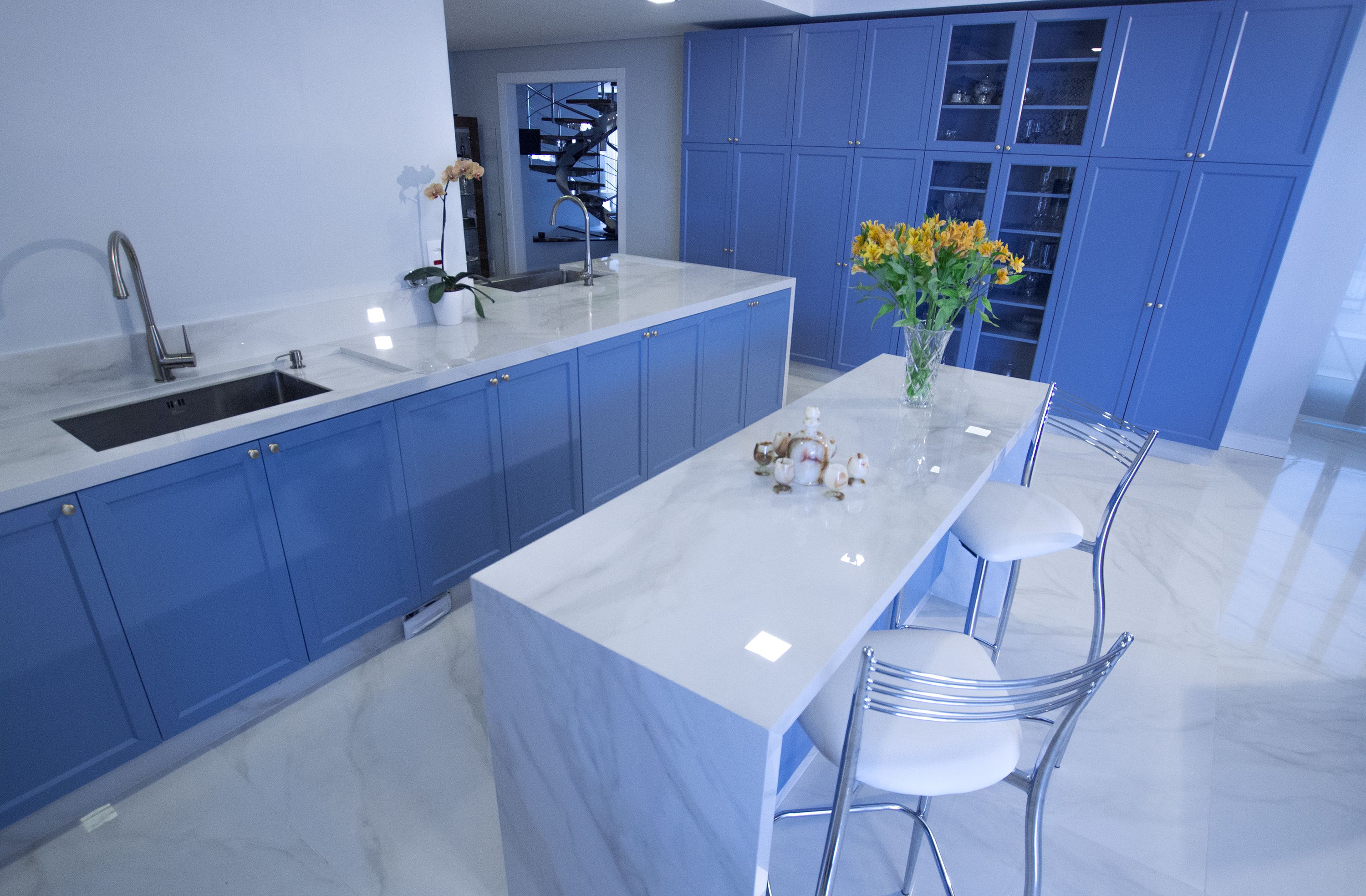 Cozinha faz um jogo entre o azul, que remete aos anos 50, e o moderno porcelanato com efeito de mármore branco