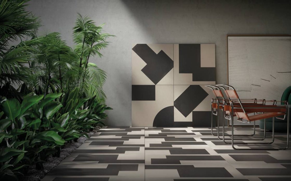 Projeto de interiores com revestimento geométrico da linha Soma da Portobello aplicado no piso e na parede, combinação de formas abstratas em preto e off-white, mobiliário moderno e vegetação lateral