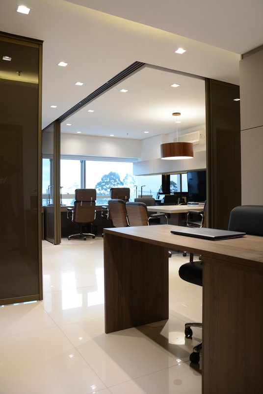 O piso com porcelanato bege deixa o escritório com aspecto profissional e contrasta perfeitamente com madeira, metal e couro (Projeto: Bibiana Menegaz)