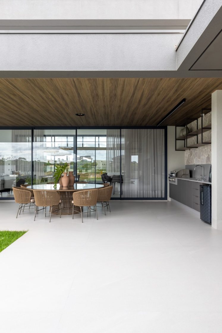 Área externa com piso que reproduz limestone, mesa com cadeiras rústicas e espaço gourmet