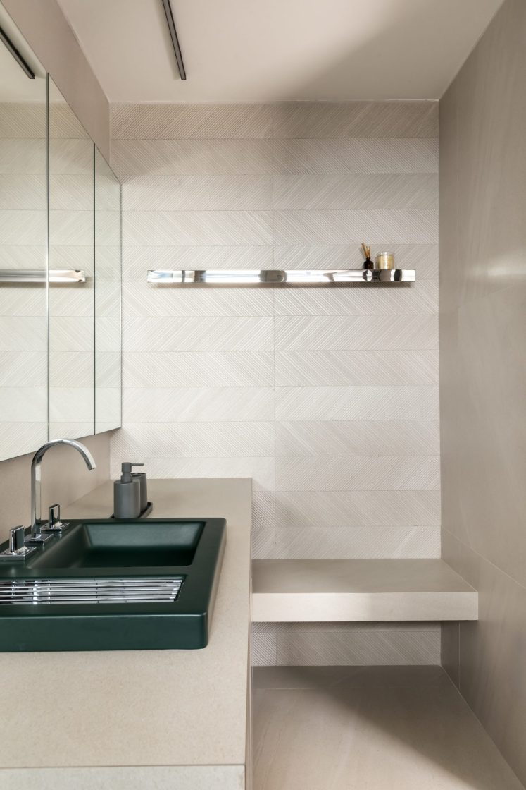 Banheiro com revestimento que reproduz limestone e parede com textura e cuba verde escura
