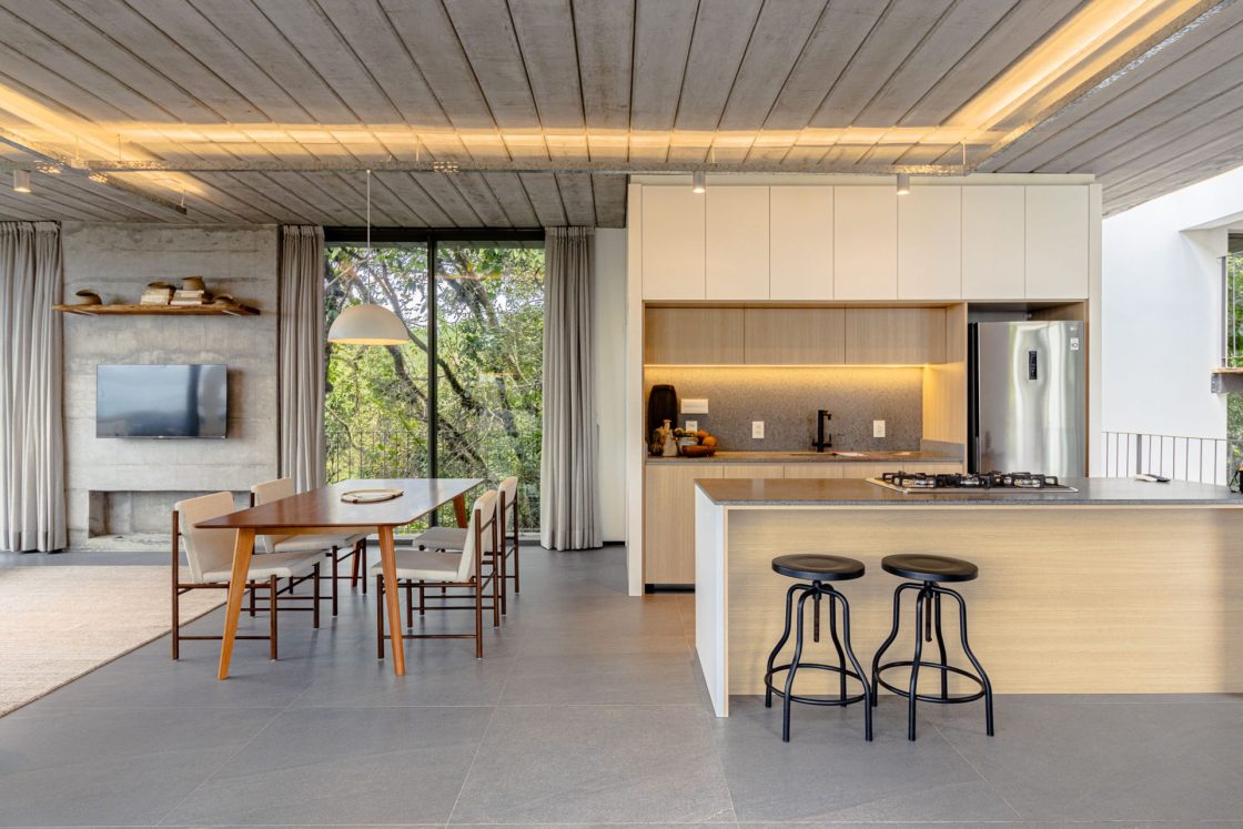 Living integrado à sala de jantar e à cozinha com ilha. Todos os espaços com piso que reproduz limestone cinza