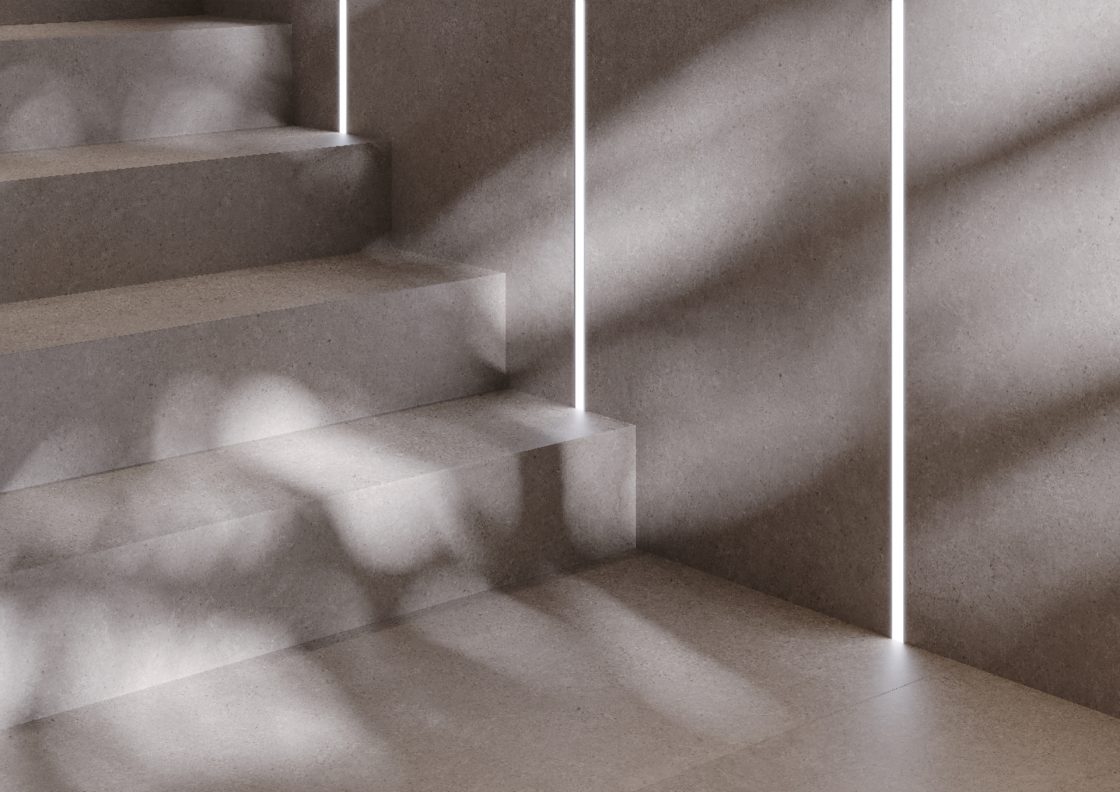 Escada cinza com iluminação em filete de luz, revestimento que remete ao concreto