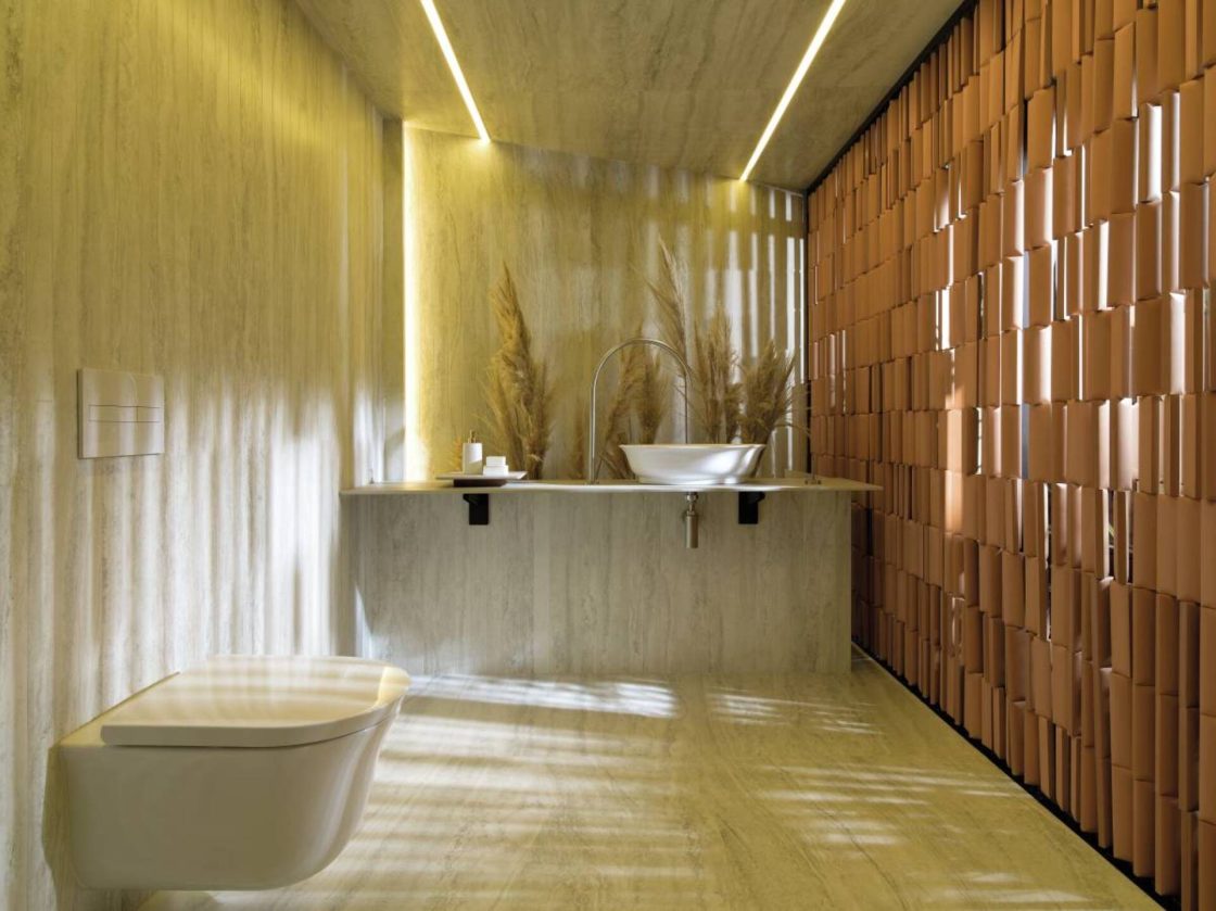 Banheiro cinza intimista com elementos naturais e entrada de luz do sol