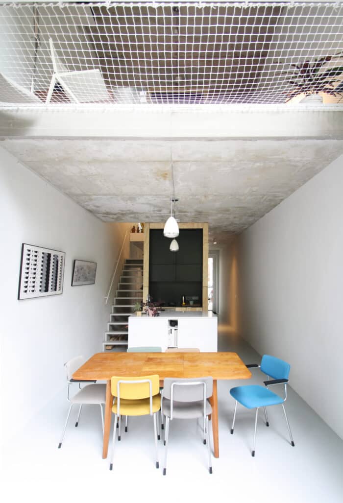 sala estreita e mesa com bancos coloridos da casa sustentável