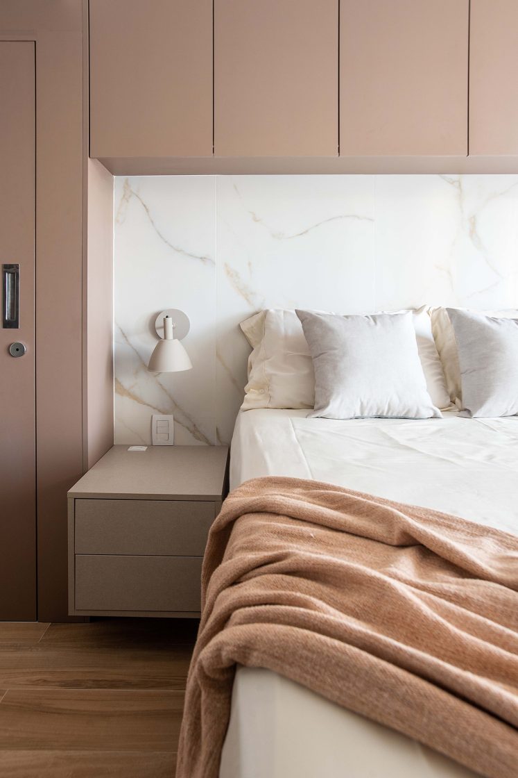 Quarto de casal em tons de rosa e branco, com cabeceira de porcelanato