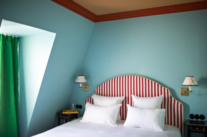 quarto com parede azul e cabeceira listrada vermelha