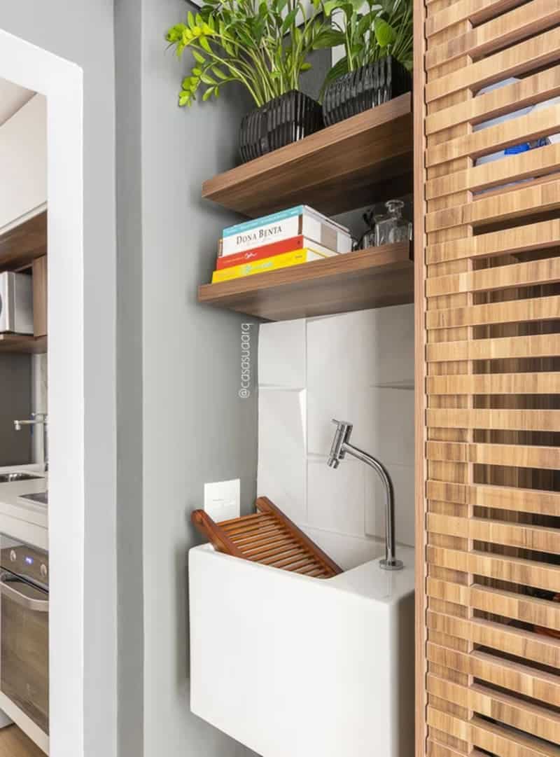 armário suspenso de madeira e máquina de lavar acoplada em uma área de serviço otimizada e integrada