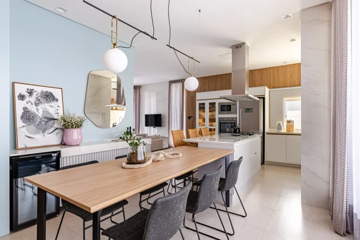 Cozinha com ilha e mesa de jantar, uma decoração maximalista e elementos em madeira, cinza e azul.