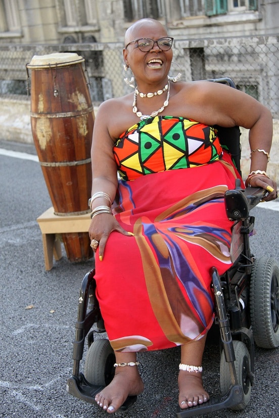 Mulher sorridente em cadeira de rodas com roupas típicas de sua cultura