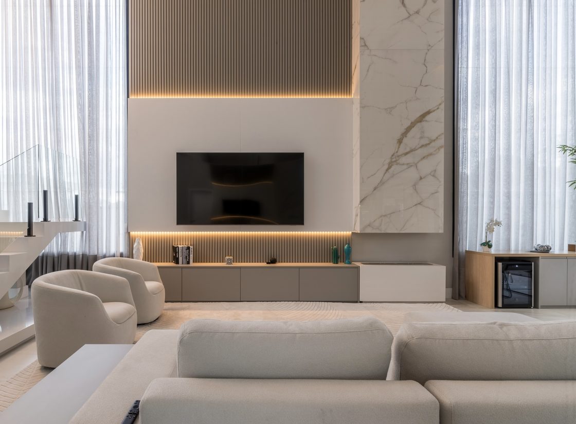 Sala em tons neutros e claros com lareira em porcelanato marmorizado branco junto ao rack