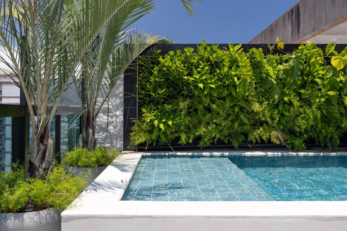 Piscina com revestimento azul Barlavento, da Portobello, e parede verde ao fundo