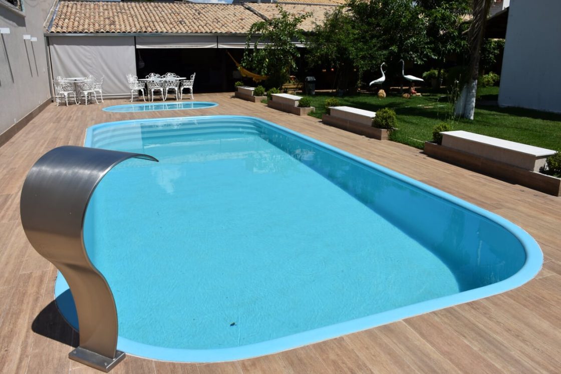 Área externa com piscina em fibra de vidro azul e revestimento amadeirado no entorno