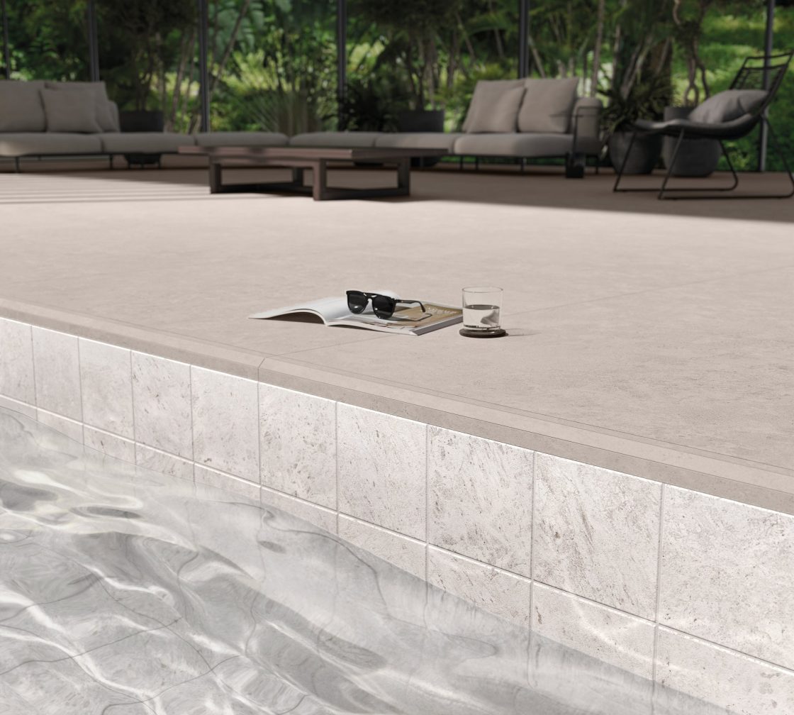 Piscina de alvenaria em tom claro com revestimento bege no entorno