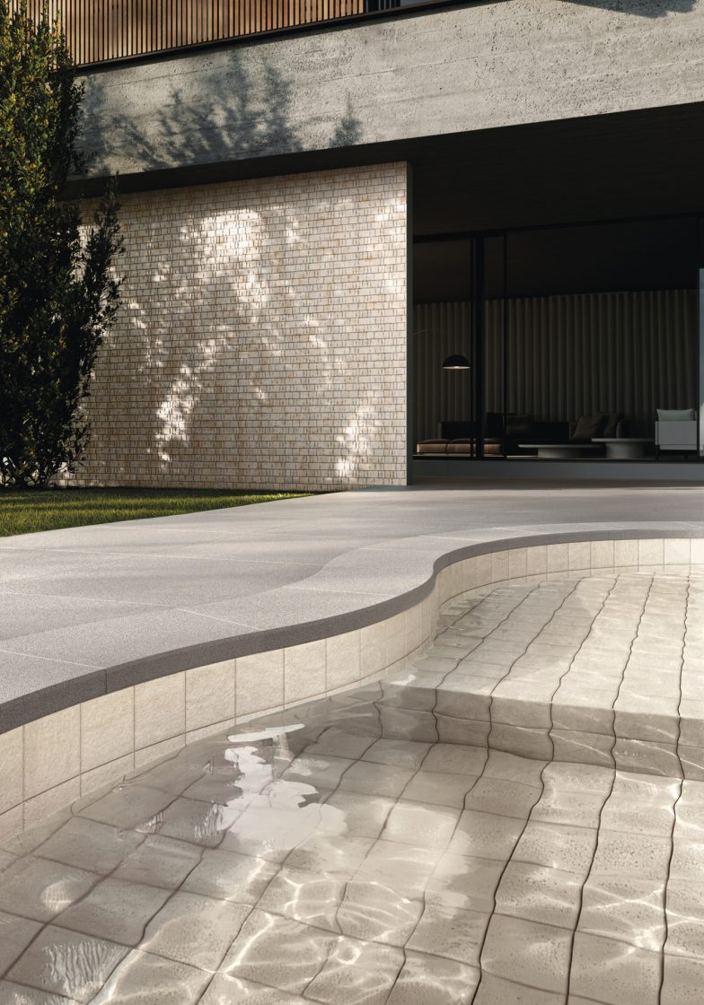 Área externa com piscina de alvenaria com revestimento Aeterna, que reproduz travertino