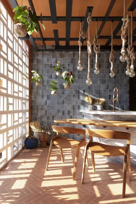 Cozinha com iluminação natural, mesa e cadeiras de madeira próximas a uma bancada