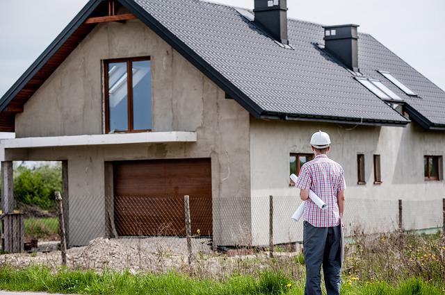 Homem de costas olhando para uma casa em construção.