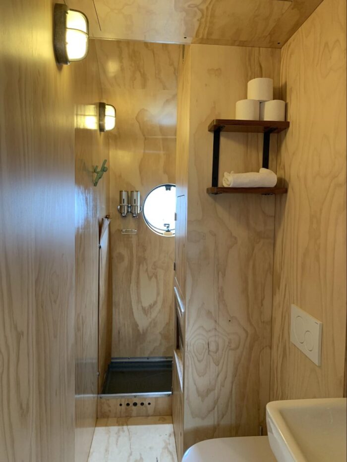 Banheiro com chuveiro, vaso sanitário, pia e armário embutido