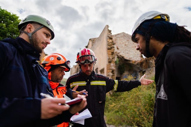 Quatro profissionais de construção civil analisando um projeto em frente a uma obra.