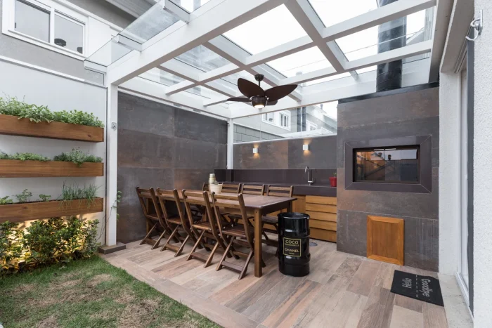 Cozinha externa rústica com elementos em madeira, churrasqueira e jardim vertical