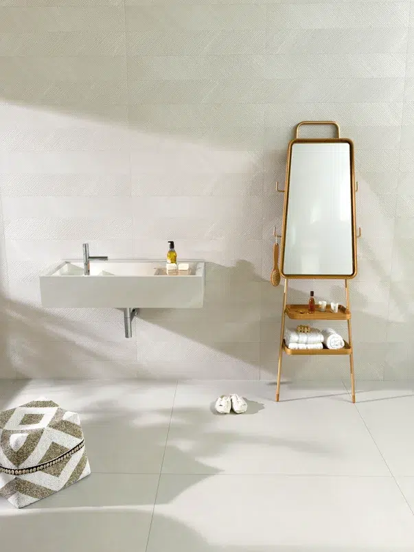 Banheiro com cores claras, com bancada pequena, espelho em um móvel de madeira