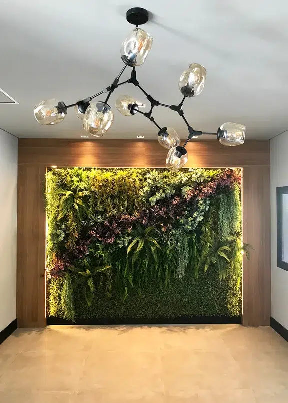 Parede de plantas no hall de entrada e um lustre minimalista.