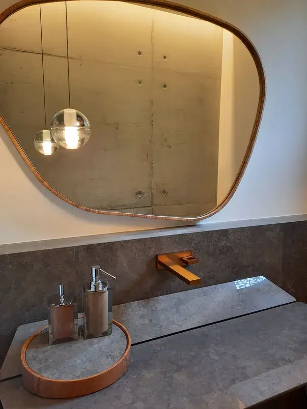 Bancada de banhiero em marmore cinza com ralo embutido, torneira e espelhos em cobre