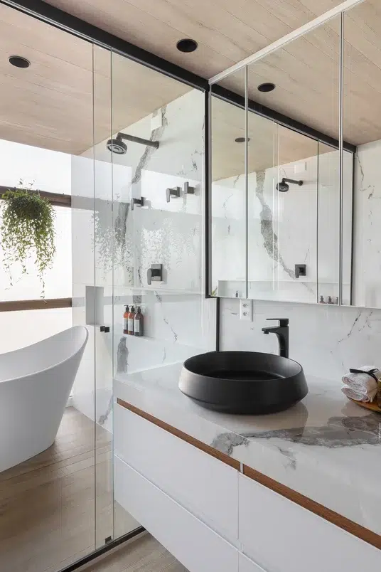 Banheiro branco com banheira, box de vidro e cuba preta