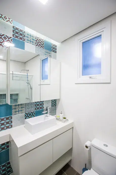 Banheiro em tons neutros e azul turquesa, com bancada e espelho duplo