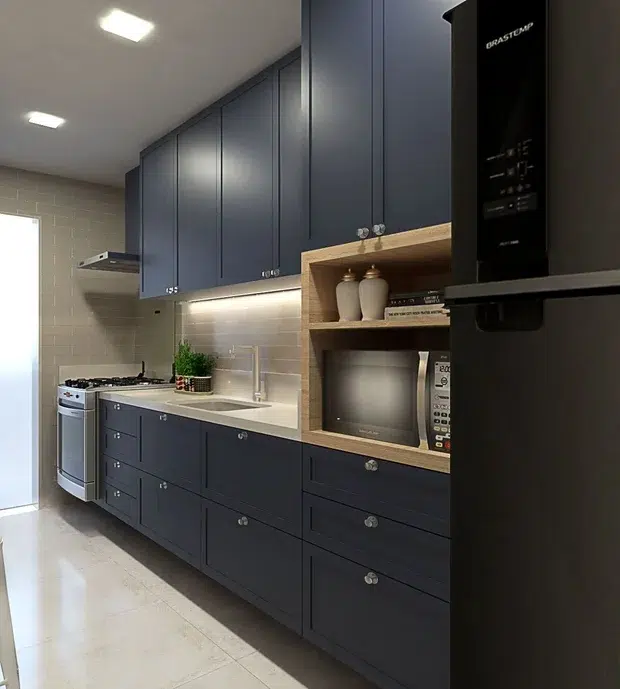 Cozinha moderna com móveis em azul petróleo. Uma geladeira e micro-ondas preto. 