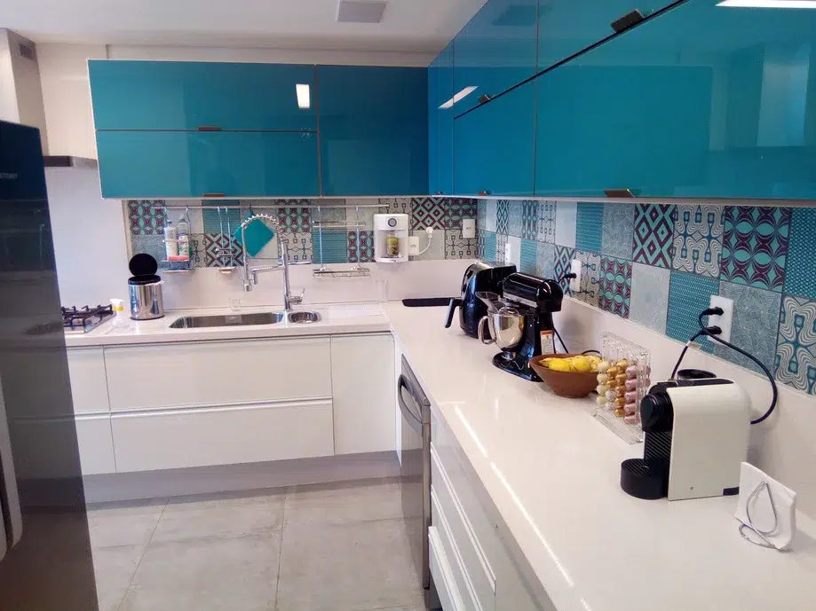 Cozinha com bancada península, detalhes em azul turquesa e armario de parede