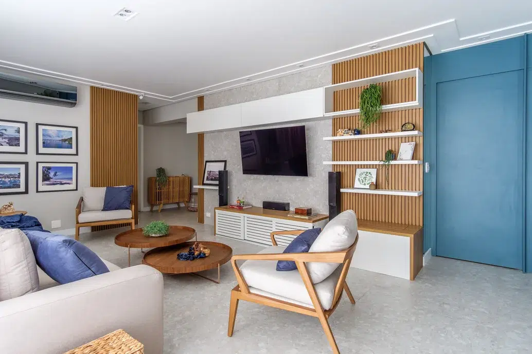 Sala de estar com painel para TV, detalhes em madeira e parede azul