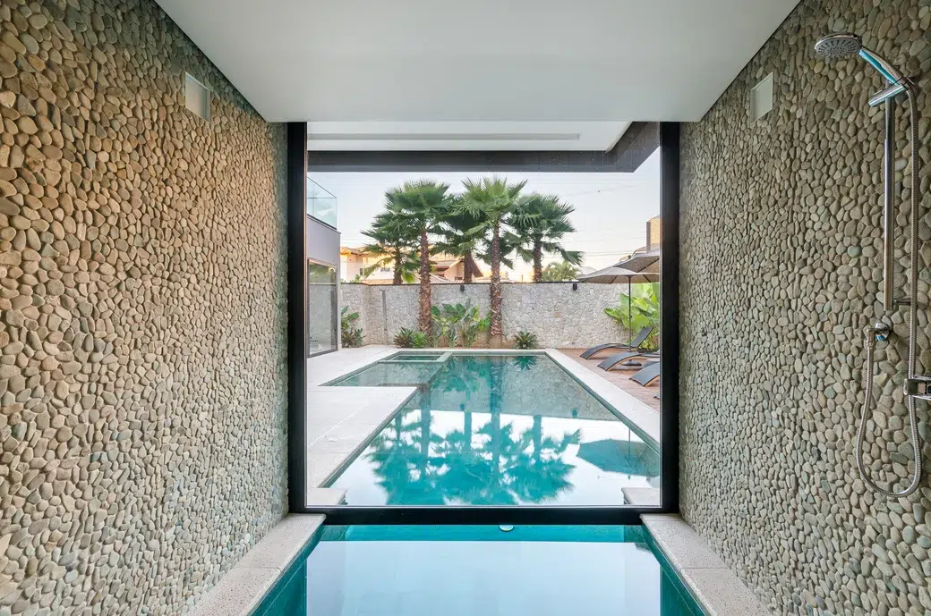 piscina e sauna divididos por uma parede de vidro e paredes com pedras