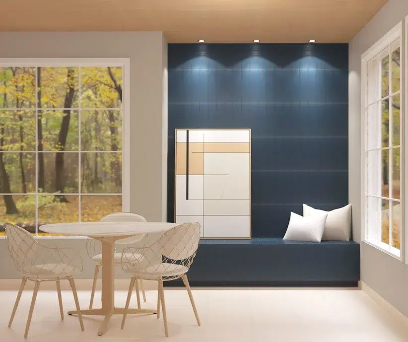 Uma sala com uma parte com parede azul petróleo, espelho e almofadas brancas. Mesa redonda e branca com três cadeiras brancas.