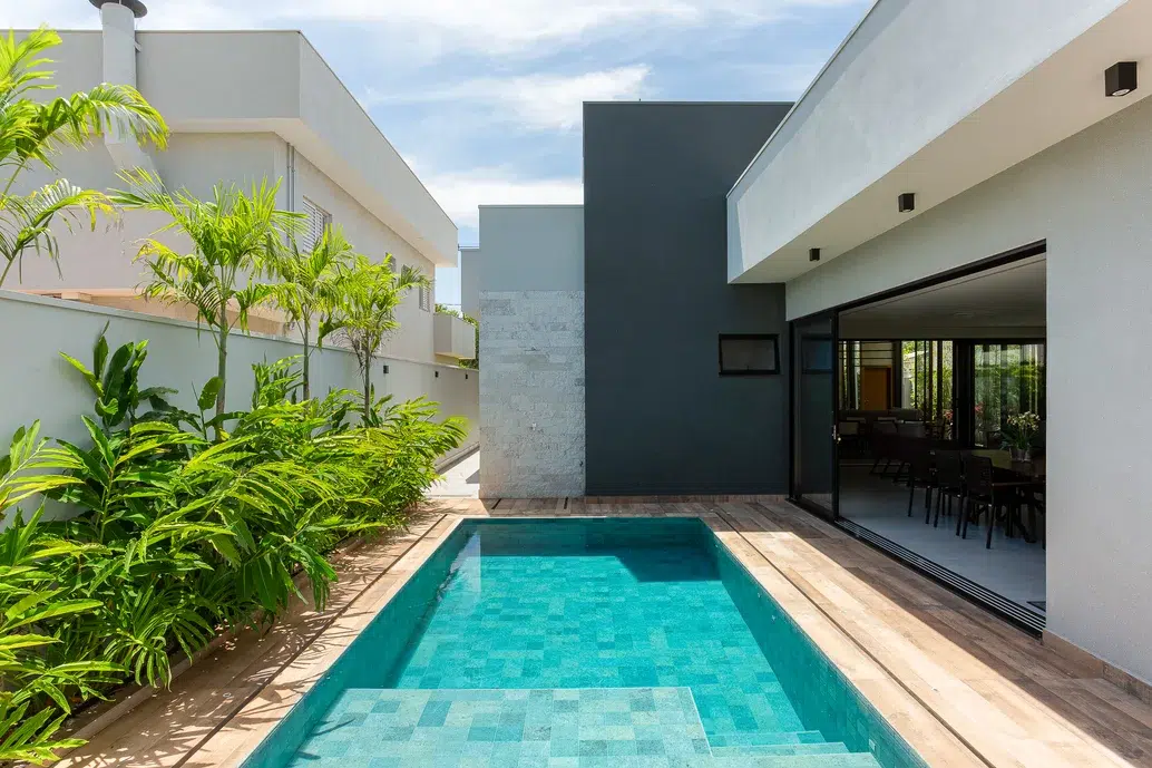 Área de piscina de uma casa com revestimento de madeira e plantas na vertical.
