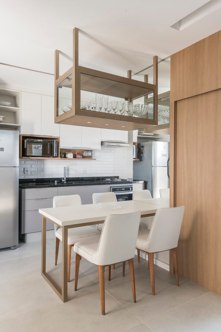 Cozinha americana em apartamento pequeno no qual a mesa com cadeiras dividem os ambientes.
