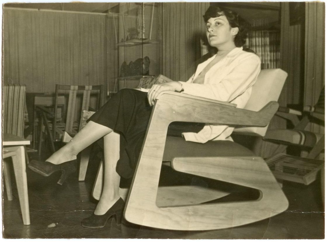 Lina Bo Bardi posa na poltrona de balanço que criou em 1951