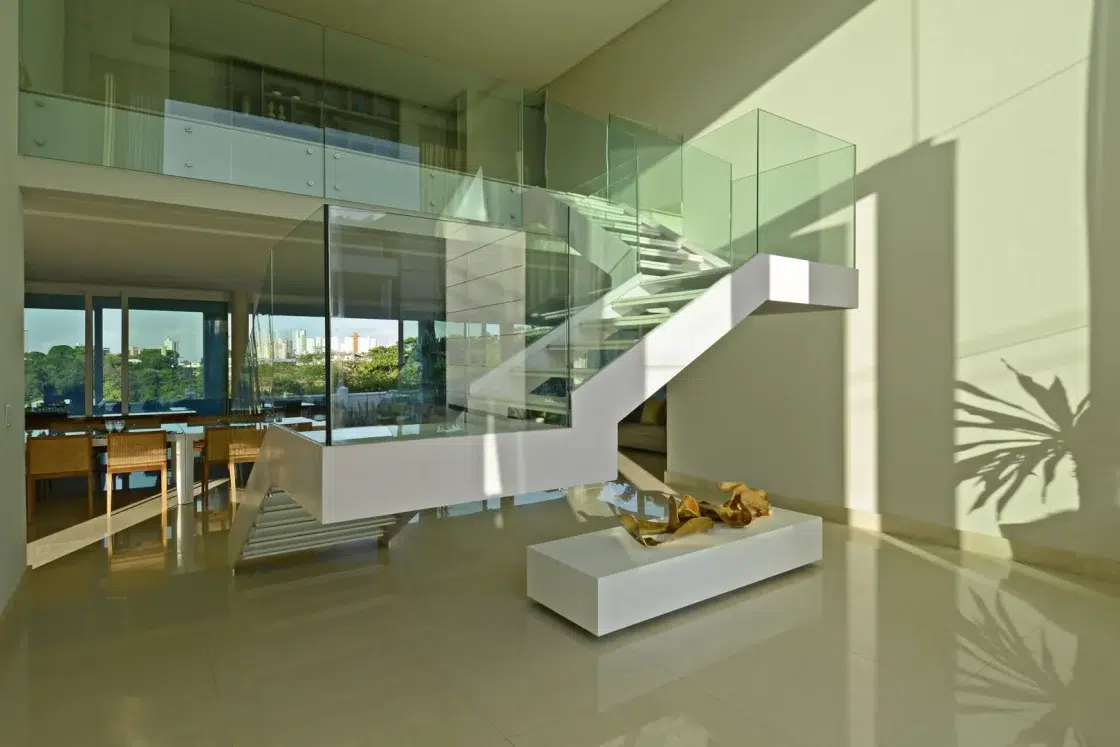 Escada com guarda-corpo de vidro com acesso ao mezanino de uma sala