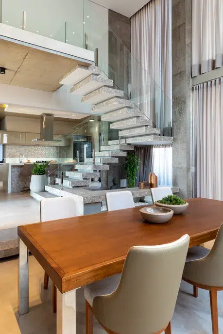 Sala de estar e cozinha de uma casa com uma escada em concreto.