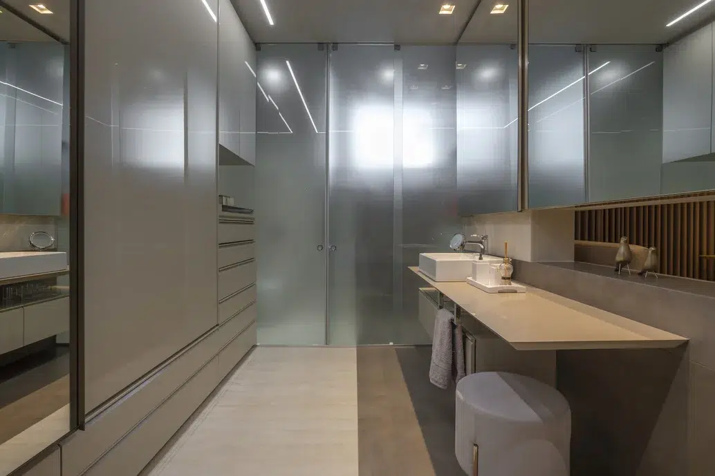 Banheiro cinza retrô com uma pia comprida e moveis na vertical.