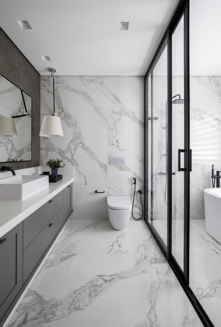 Banheiro amplo e elegante com porcelanato marmorizado no piso e nas paredes